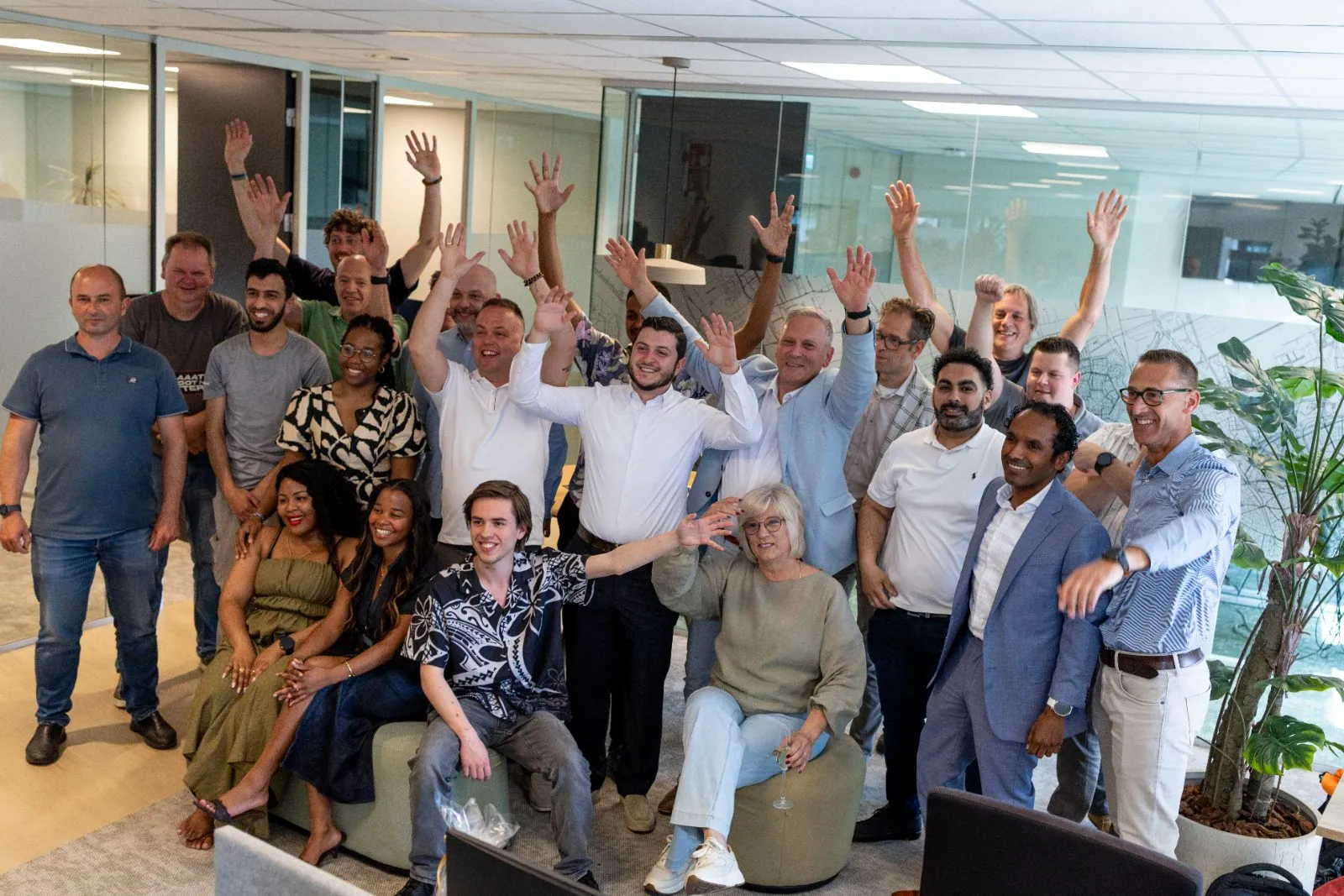 Team van Micros poseert samen in de kantoortuin, lager fotostandpunt.